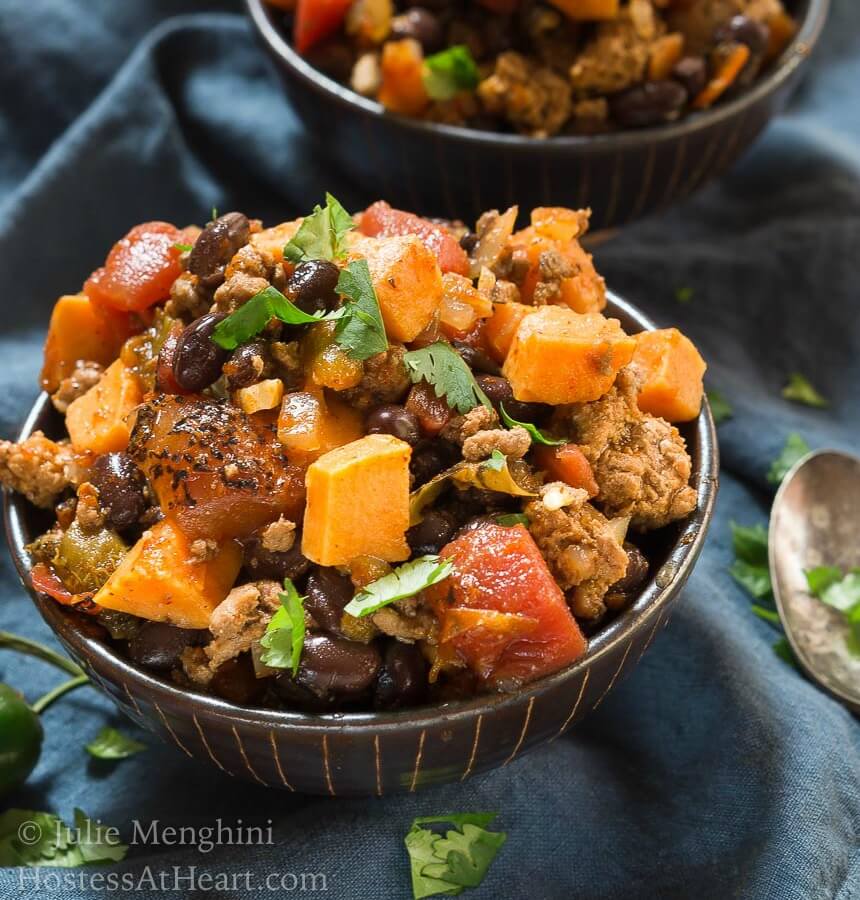 Two bowls of Sweet Potatoe and Black Been Chili sitting on a blue napkin.