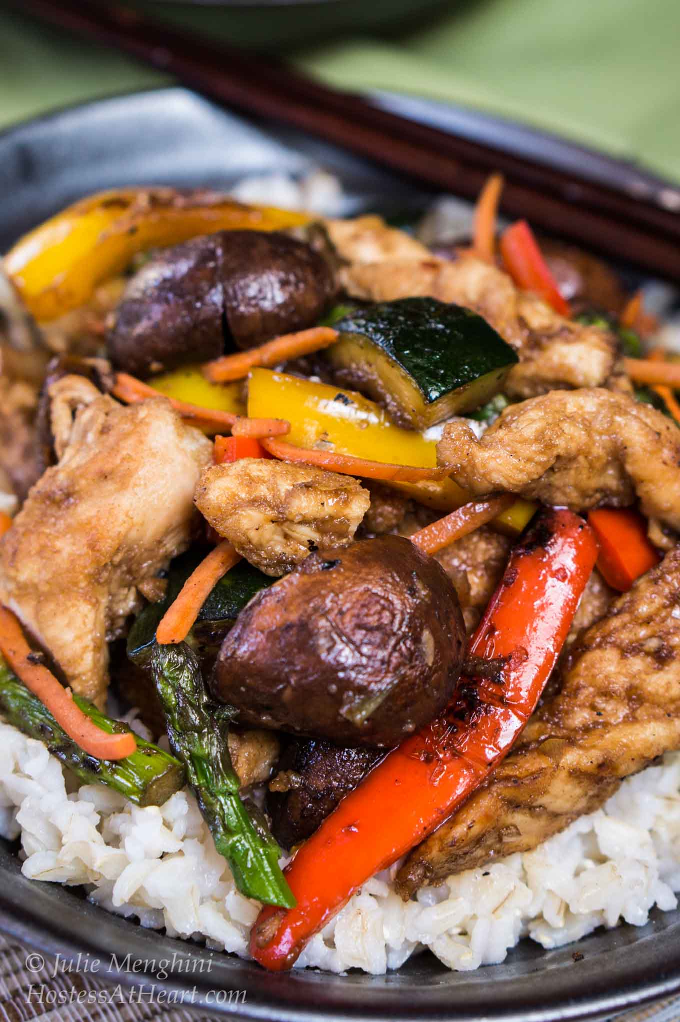 A bowl of white rice topped with chicken and vegetable stirfry