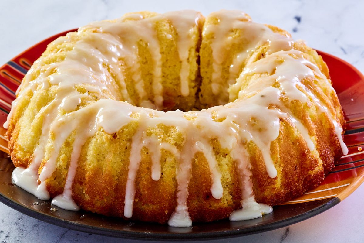 Side view of a lemon olive oil bundt cake drizzled with glaze. - Hostess At Heart