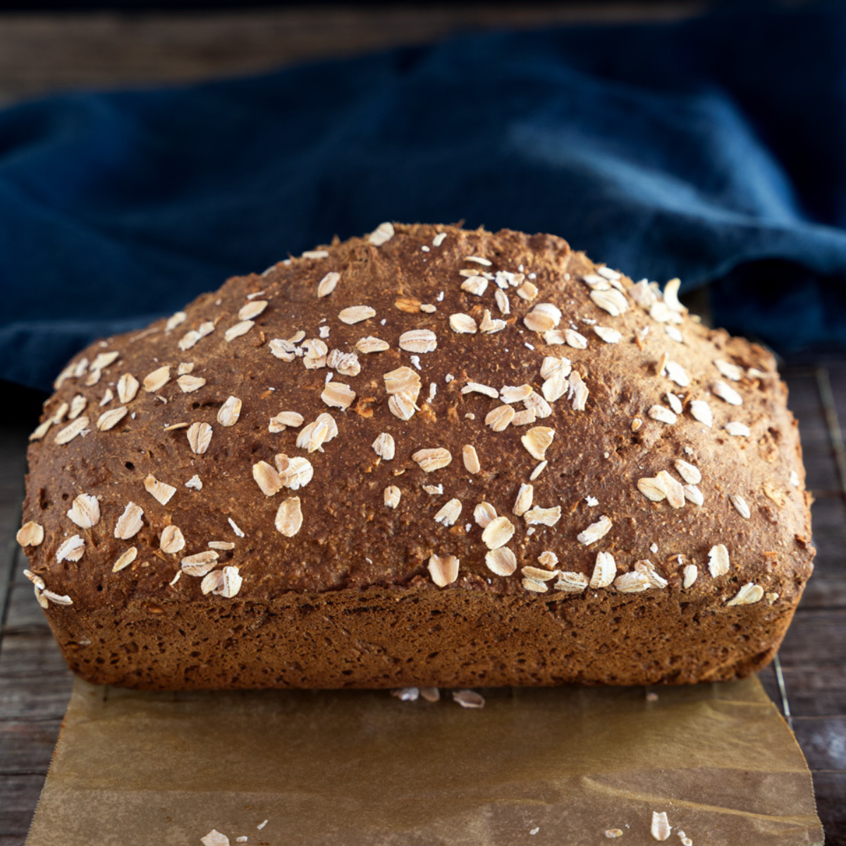 Whole loaf of Irish Brown Bread on a cooling rack with a blue cloth in the background.