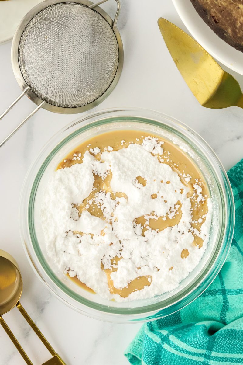Irish Cream and powdered sugar added to a mixing bowl to make a cake glaze.