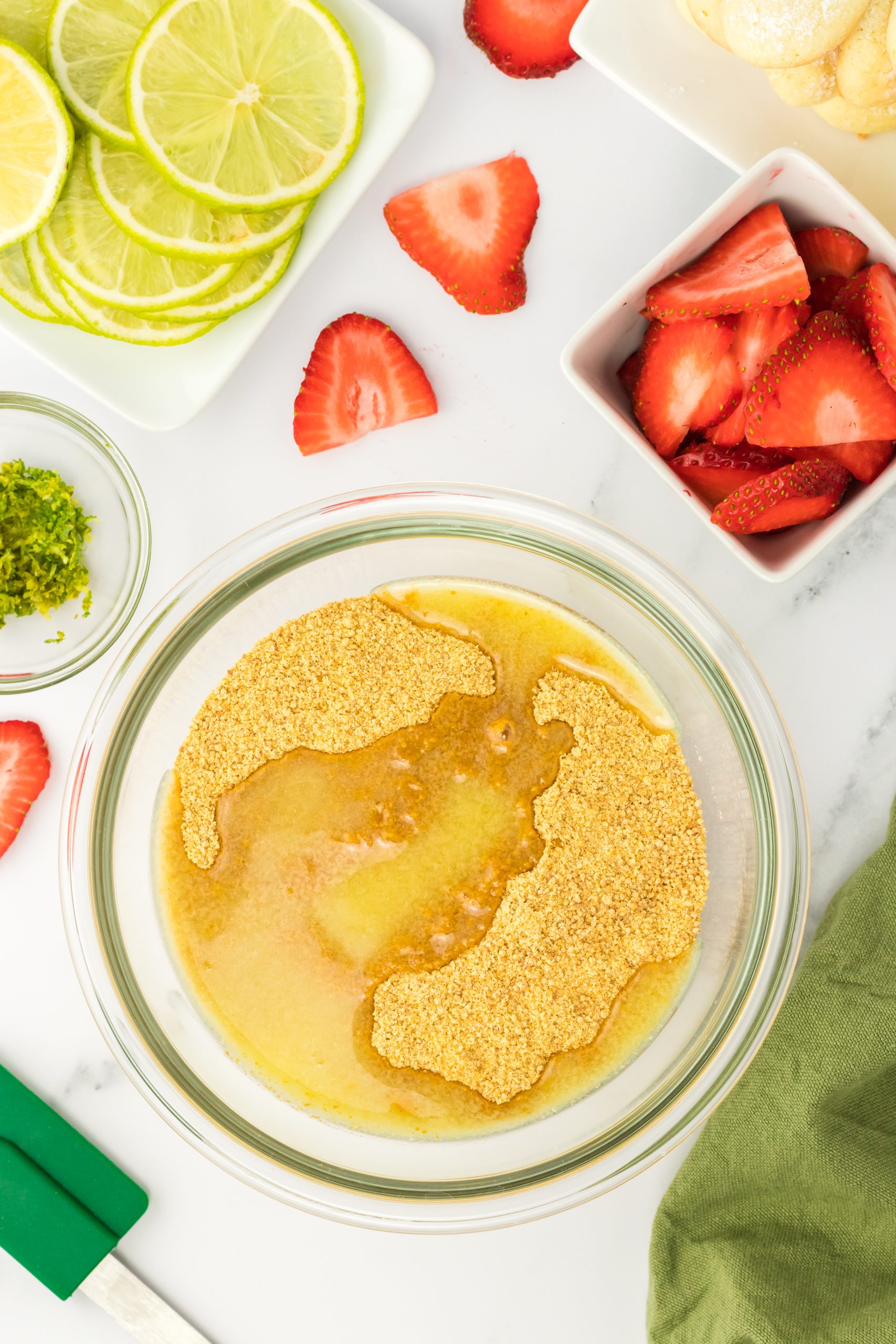 Top-down view of melted butter with graham cracker crumbs in mixing bowl.