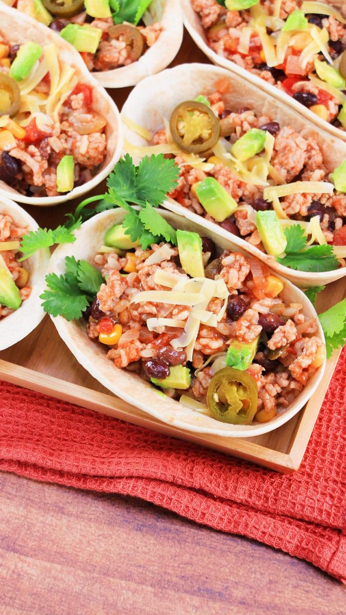 Green Chili Pork Tacos garnished with fresh cilantro, avocado and jalapenos